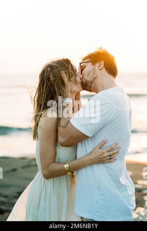 L'uomo bacia una donna che tiene la testa tra le mani Foto Stock