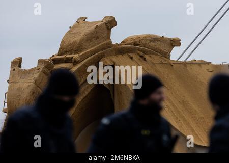 Lützerath, Germania. 05 gennaio 2023, Renania settentrionale-Vestfalia, Lützerath: Gli agenti di polizia si trovano di fronte a un escavatore della lignite direttamente sul bordo di demolizione della miniera di lignite Garzweiler II opencast. Secondo le loro stesse dichiarazioni, la polizia ha nuovamente eliminato una barricata nel villaggio lignite occupato di Lützerath. Ciò è stato fatto per motivi di sicurezza. Foto: Rolf Vennenbernd/dpa Credit: dpa picture Alliance/Alamy Live News Foto Stock