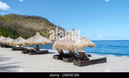 Sedie a sdraio e ombrelloni su una spiaggia tropicale a St lucia, spiaggia bianca con palme Caraibi Foto Stock