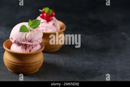 Misurini rosa di pistole con ribes rosso su un tavolo nero. Gelato Foto Stock