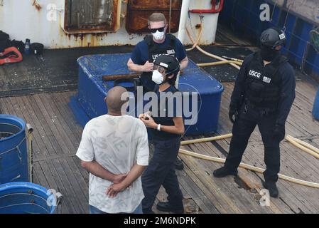 La Guardia Costiera ausiliaria Hua Lin McCaffrey assiste una squadra d'imbarco dalla Guardia Costiera Cutter Munro durante un imbarco in mare nell'Indo-Pacifico, 2 maggio 2022. I volontari con capacità di interpretazione come McCaffrey sono molto richiesti nella Guardia Costiera ausiliaria, per aiutare la Guardia Costiera a rilevare e scoraggiare la pesca illegale, non dichiarata e non regolamentata. Foto Stock