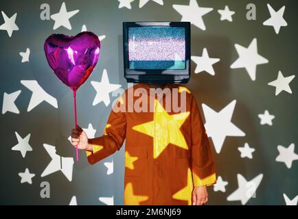 L'arte surreale di TV addicted l'uomo con la tv invece di testa che tiene la mongolfiera dell'elio sulla festa. Foto Stock