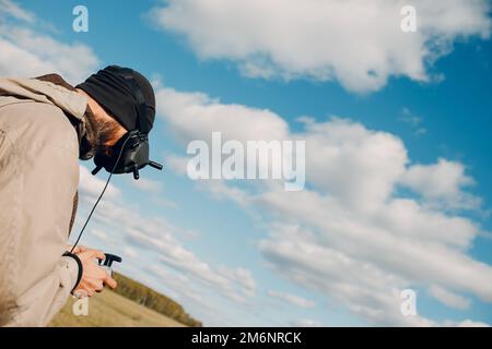 Uomo che controlla il drone quadricottero fpv con occhiali di protezione telecomando antenna Foto Stock