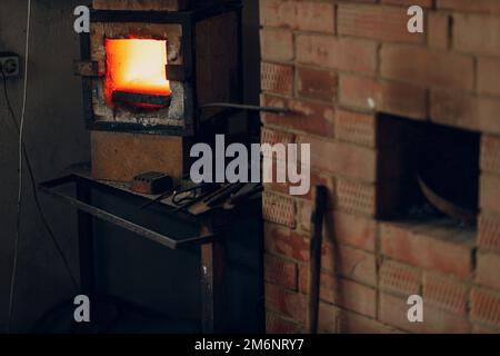 Forno di fucina con fiamma calda. Smith scaldante pezzo di acciaio in fuoco di fucina rosso-caldo Foto Stock