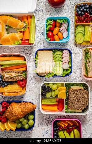 Shot di lunchboxes scuola con vari pasti nutrienti sani su sfondo di pietra Foto Stock