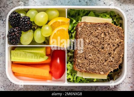 Pranzo al sacco a scuola verde con panino, frutta fresca, cetriolo e carota Foto Stock