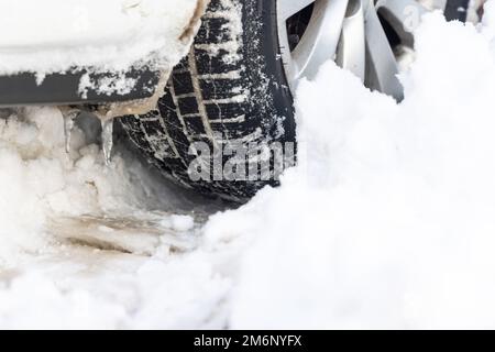 Primo piano dei pneumatici vettura in inverno sulla strada coperta di neve Foto Stock