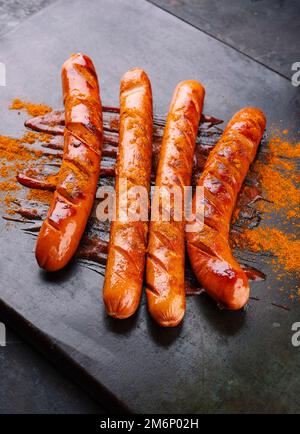 Salsicce tradizionali tedesche al curry wurst con ketchup e curry in polvere servite come primo piano su una rustica lavagna nera Foto Stock