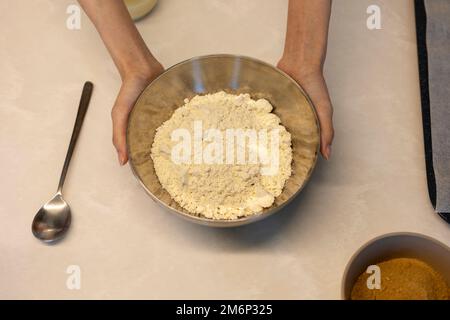 Preparare l'impasto di hotteok del pane del biscotto prima della cottura, mani che tengono la ciotola di farina Foto Stock