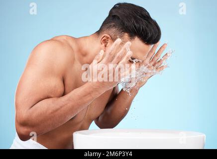 Pulire, governare e lavare il viso con acqua per la cura della pelle, l'igiene del mattino e la cura del corpo su uno sfondo blu studio. Bellezza, benessere e modello Foto Stock