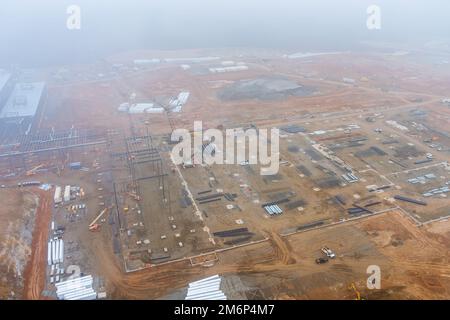 Cantiere all'alba del mattino in presenza di nebbia fitta, quando le gru usate devono lavorare in edifici commerciali Foto Stock