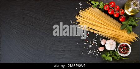 Pasta, spaghetti e ingridienti da cucina su superficie nera in ardesia. Concetto di cucina italiana, menu del ristorante, modello di ricetta. Vista dall'alto, piatto, mockup Foto Stock