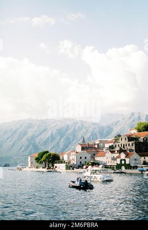 Antiche case sulla costa di Perast sulla baia di Cattaro sullo sfondo delle montagne Foto Stock