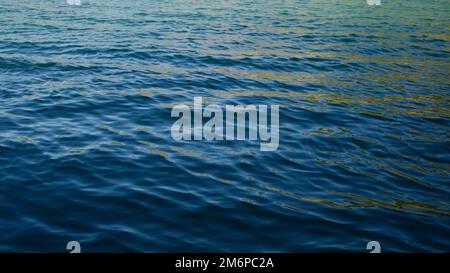 Senza onde, mare calmo al tramonto. I raggi di sole pallidi che si riflettono fuori del mare. Foto Stock