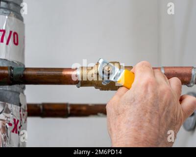 Idraulico valvola di arresto dell'acqua. Tubo idraulico in rame con valvola di alimentazione dell'acqua in ottone e maniglia del rubinetto gialla. Foto Stock