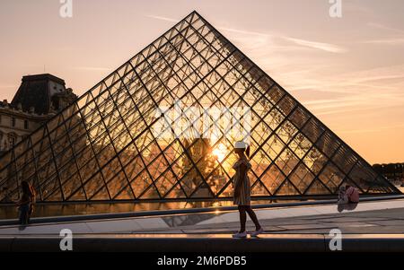 Parigi Francia Museo del Louvre piramide durante il tramonto in estate, la gente si rilassa alla luce del sole Foto Stock