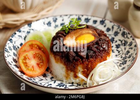 Primo piano Nasi Tim Ayam Telur Asin, riso di pollo al vapore con uovo salato. Indonesiano Comfort Street Food con influenza cinese. Foto Stock