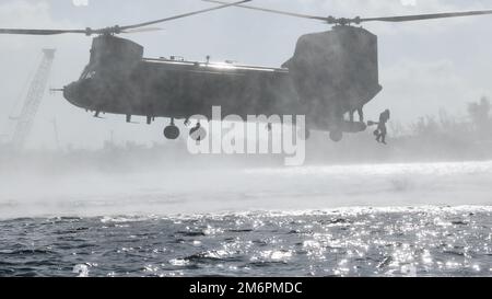 Un Beret Verde assegnato a 2nd battaglione, 10th Special Forces Group (Airborne), si lancia nel Golfo del Messico da un elicottero CH-47 Chinook vicino a Key West, Florida, 3 maggio 2022. Helocast, o free-drop da un elicottero, è un mezzo per inserire nuotatori/subacquei da combattimento e imbarcazioni per la mobilità marittima in un ambiente acqueo. Foto Stock