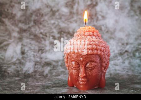 Candela a forma di testa di Buddha che brucia sul tavolo di pietra grigia Foto Stock