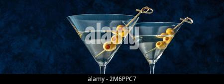 Martini, due bicchieri con panorama di olive speziate, su sfondo blu Foto Stock