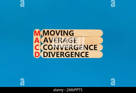Simbolo MACD. Concetto di parole MACD Moving Media convergenza divergenza su bastone di legno su bellissimo sfondo blu. Business MACD commovente media conve Foto Stock