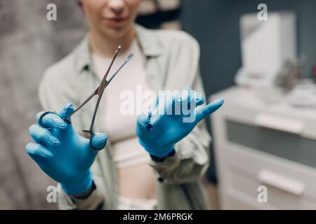 Giovane donna che fa piercing all'orecchio al salone di bellezza studio. Foto Stock