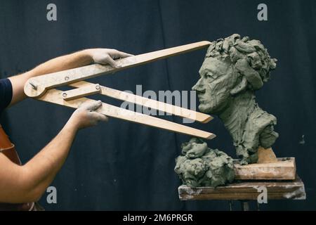 Uomo scultore crea scultura donna uomo in argilla sculpta. Laboratorio di creazione di statue artigianali Foto Stock