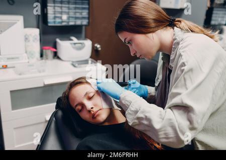 Giovane donna che fa piercing all'orecchio al salone di bellezza studio. Foto Stock