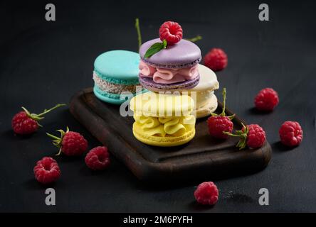 Una pila di macaron multicolore su un asse di legno. Foto Stock