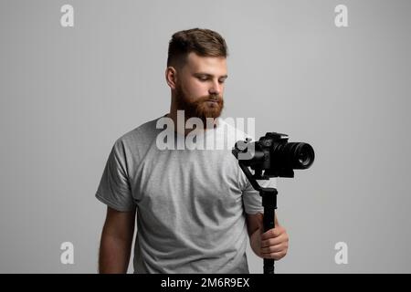 Cameraman professionista con una fotocamera gimbal. Concetto di filmmaking, videografia, hobby e creatività. Foto Stock