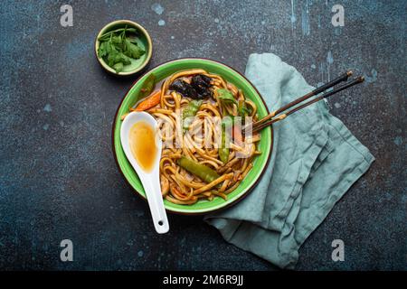 Zuppa asiatica con noodle di udon, pollo e verdure in un recipiente in ceramica verde Foto Stock