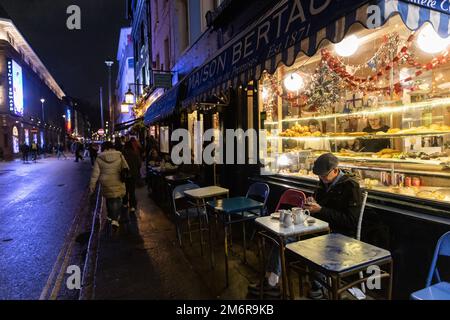 Un uomo si siede da solo fuori Mason Bertaux, famoso negozio di dolci in Greek Street, Soho, Londra, che produce freschi focaccine artigianali, cheesecake, tè alla crema ecc. Foto Stock