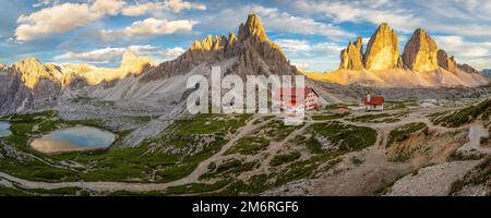 Vista del rifugio Dreizinnenhuette e cappella con lago di montagna massiccio roccioso Paternkofel e montagne tre cime al tramonto, panorama Foto Stock
