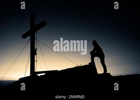 Gli alpinisti alla croce sommitale del Namloser Wetterspitze al tramonto con Lechtaler Alpen, Namlos, Reutte, Lechtal, Ausserfern, Tirolo, Austria Foto Stock