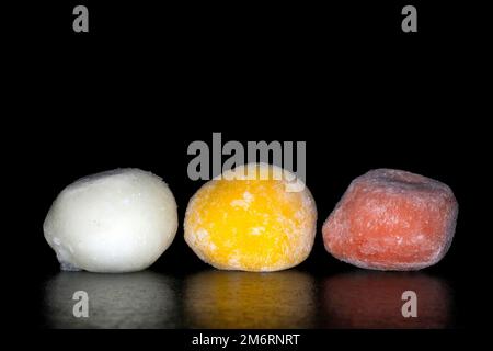 Gelato giapponese mochi ripieno di yuzu, mango e fragola, fotografia alimentare con sfondo nero Foto Stock