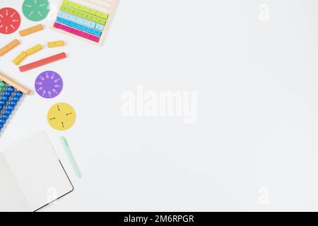Risorse per l'apprendimento della matematica su sfondo bianco. Abilità matematiche iniziali. Abaco colorato, frazioni matematiche, notebook di carta aperta e penna su scrivania bianca. In alto Foto Stock