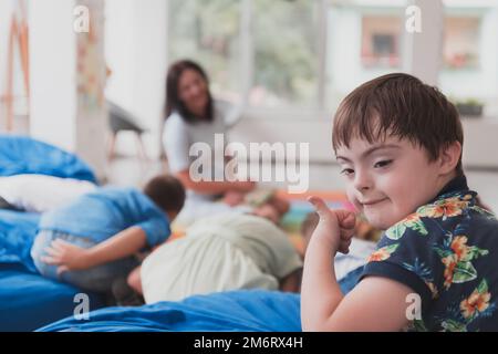 Un ragazzo con la sindrome di Down passare del tempo insieme in un istituto prescolare e giocare ai giochi Foto Stock