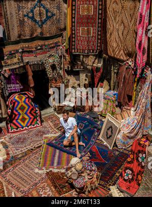 Giovane uomo in un vecchio tradizionale negozio di tappeti turchi nella grotta casa Cappadocia, Turchia Kapadokya Foto Stock