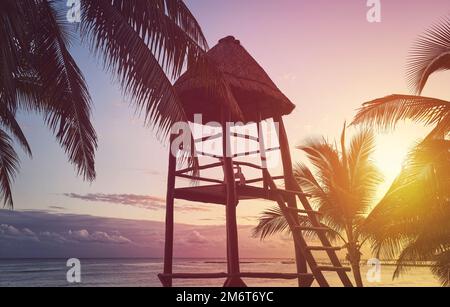 Bagnino torre silhouette su una spiaggia caraibica al tramonto, tonalità di colore applicato, Messico. Foto Stock