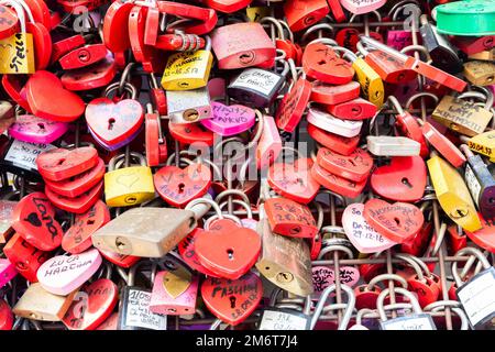 Verona, Italia - Giugno 2022: Sfondo di chiuse a forma di cuore su una parete, simbolo dell'amore per sempre. Foto Stock