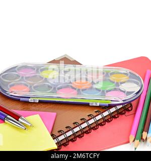 Acquerelli, quaderni e altri materiali scolastici isolati su sfondo bianco. Con spazio libero per il testo. Foto Stock