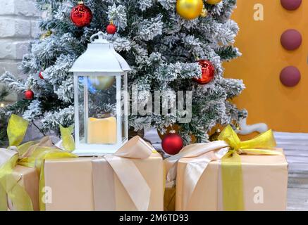 Lanterna bianca di Natale con una candela sulle scatole con i regali di Natale. Foto Stock