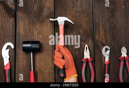 Un set di utensili da costruzione su uno sfondo di legno marrone, vista dall'alto. Martello, pinze, chiave regolabile Foto Stock