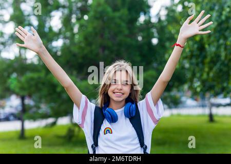 ragazza in età adolescente con zaino e cuffia nel concetto di ritorno a scuola parco Foto Stock