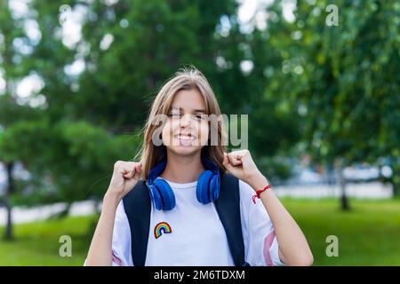 ragazza in età adolescente con zaino e cuffia nel concetto di ritorno a scuola parco Foto Stock