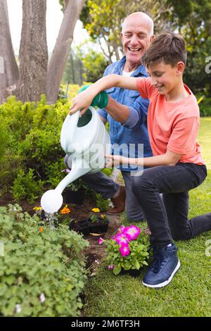 Nonno caucasico e nipote trascorrono del tempo insieme nel giardino, piantando Foto Stock