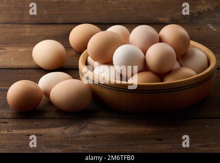 Uova fresche di pollo in un piatto rotondo di legno sul tavolo Foto Stock