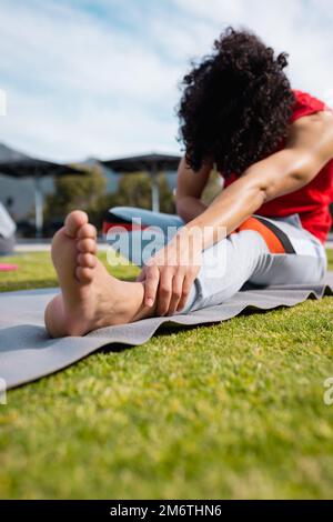 Uomo biraciale che pratica yoga e stretching in giardino Foto Stock