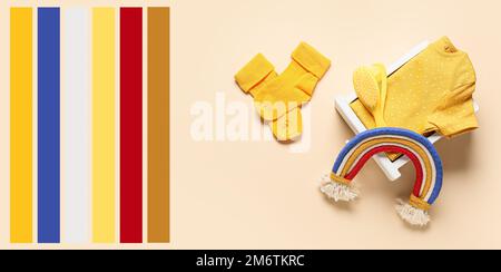 Scatola con abiti gialli e giocattolo arcobaleno su sfondo chiaro. Diversi motivi di colore Foto Stock