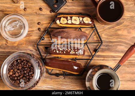 Griglia con gustose cialde di cioccolato, caffè caldo e fagioli su sfondo di legno Foto Stock